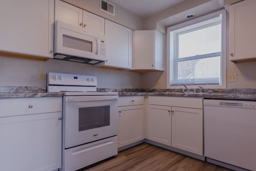 a kitchen with white cabinets and white appliances and a window