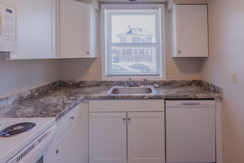 a kitchen with white cabinets and granite counter tops and a window