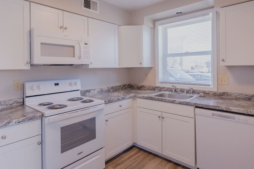 a kitchen with white appliances and granite counter tops and a window