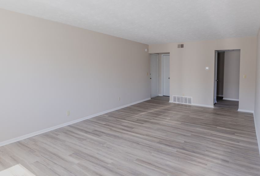 an empty living room with wood floors and white walls