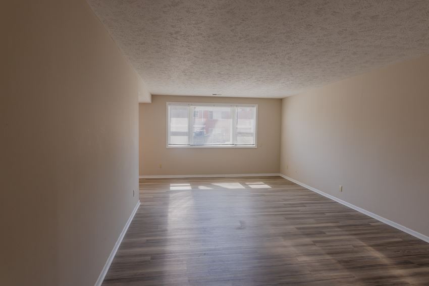 an empty living room with wood floors and a window