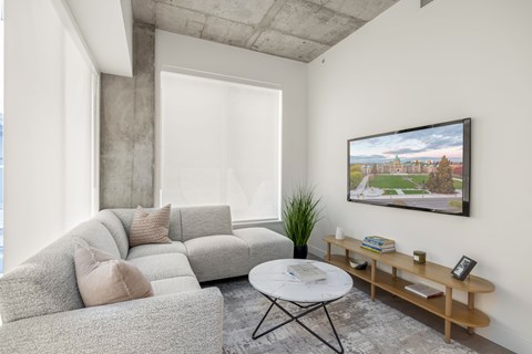 A living room with a grey couch, a white coffee table, and a painting on the wall.