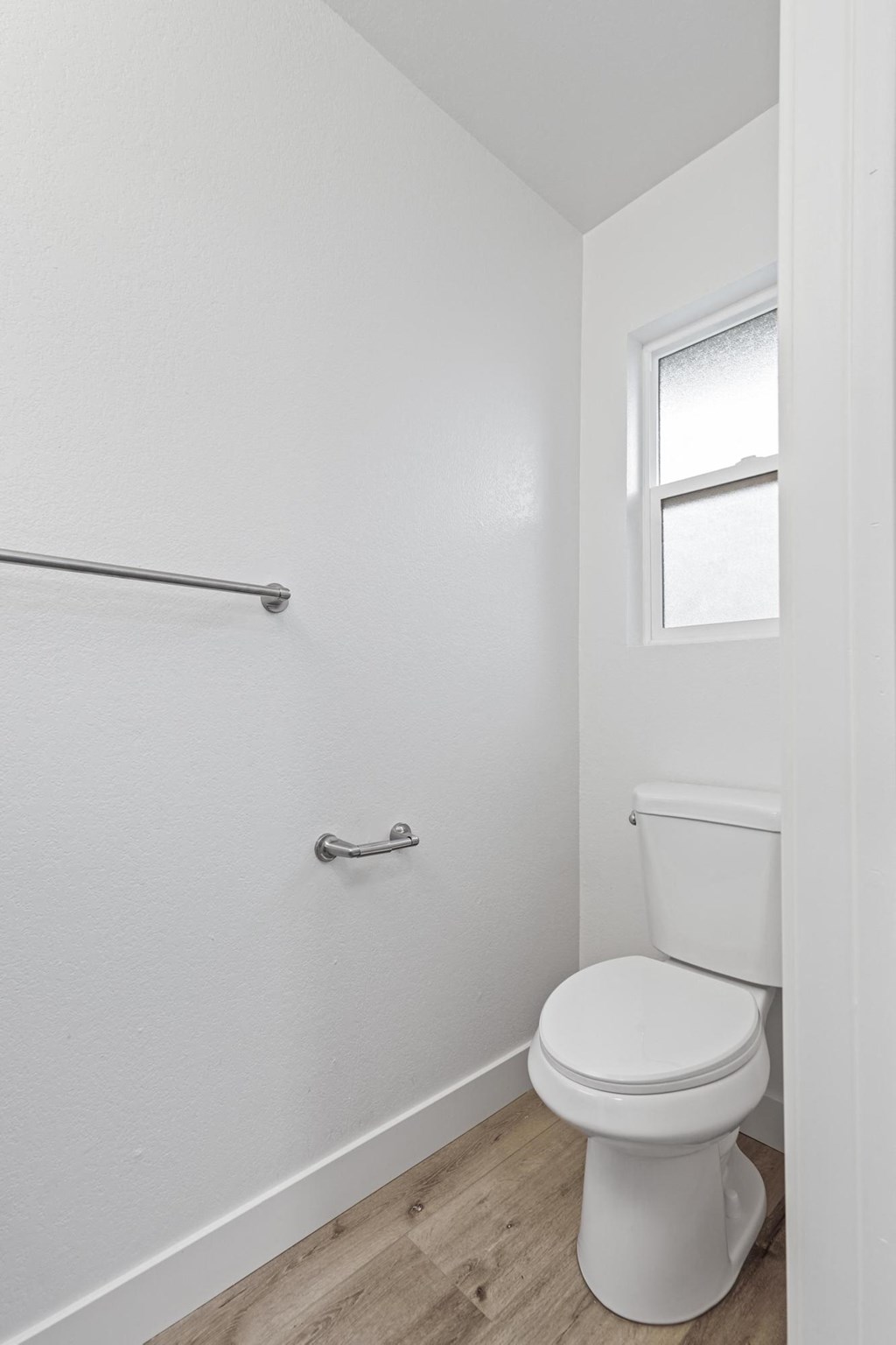 A white toilet in a small bathroom with a window at Stony Creek Apartments, Santa Rosa, CA
