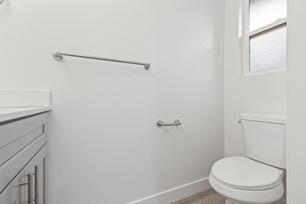 A white toilet in a small bathroom with a window at Stony Creek Apartments, California, 95401