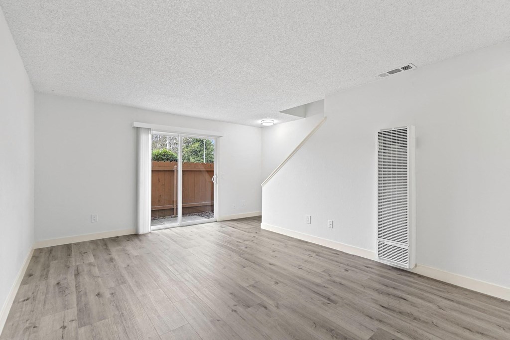A room with a white ceiling, wooden floors, and a window with a view of a backyard at Stony Creek Apartments, Santa Rosa