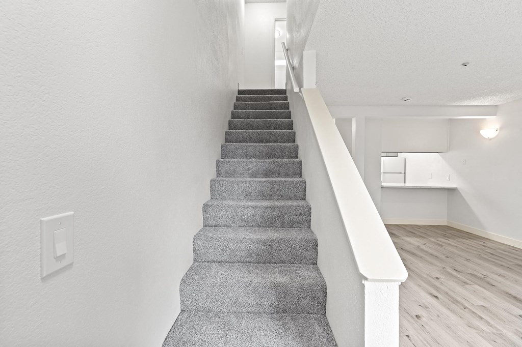 A staircase with a white railing and grey carpeted steps at Stony Creek Apartments, California, 95401