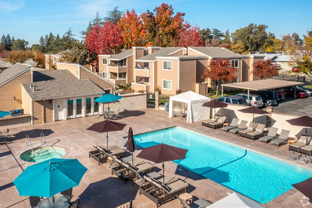 a swimming pool with umbrellas in front of a apartment complex