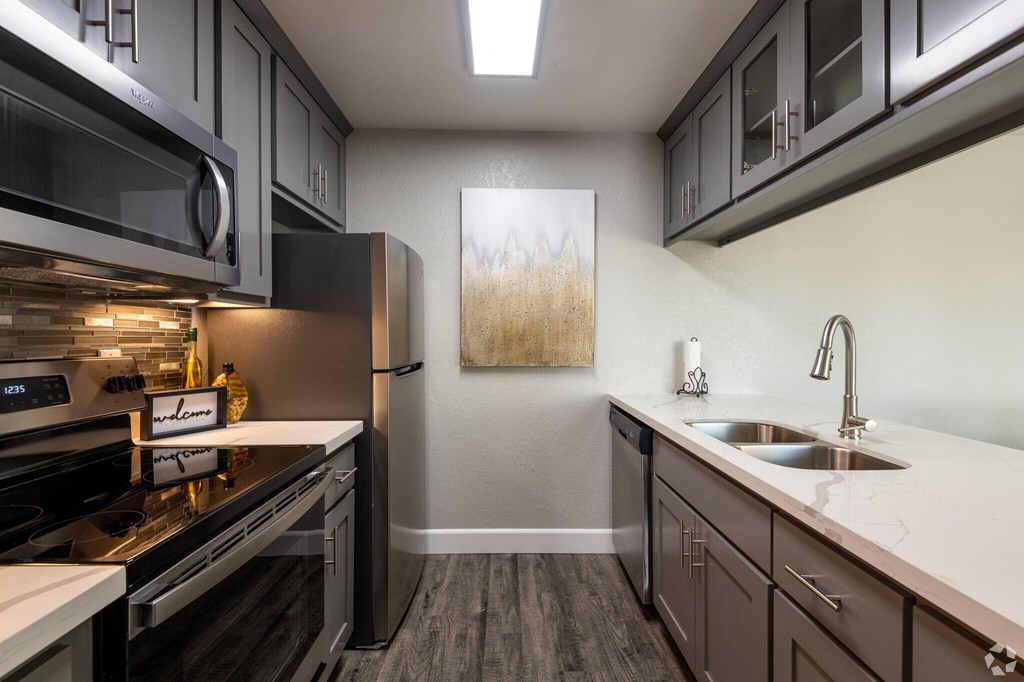 a kitchen with stainless steel appliances and white counter tops and a sink