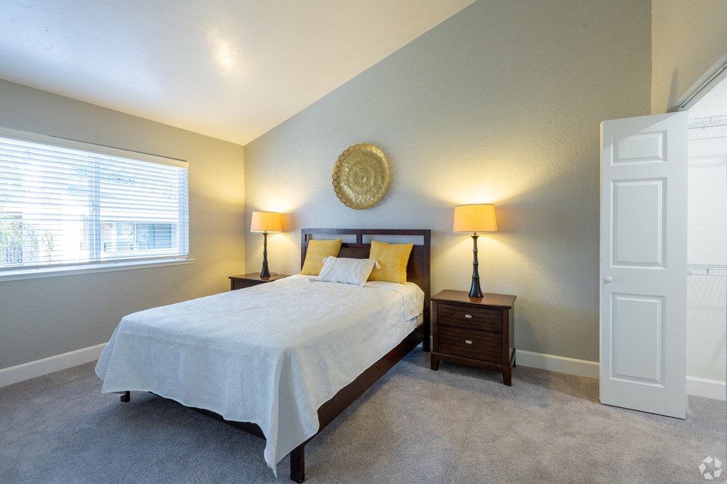 a bedroom with a bed and two lamps and a window