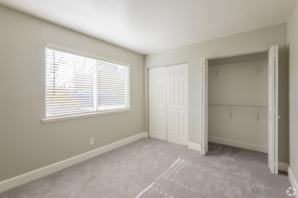 an empty room with a window and a closet