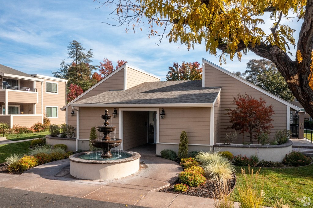 a fountain sits in front of a small tan house