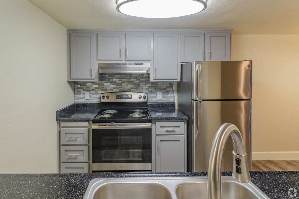 a kitchen with grey cabinets and stainless steel appliances