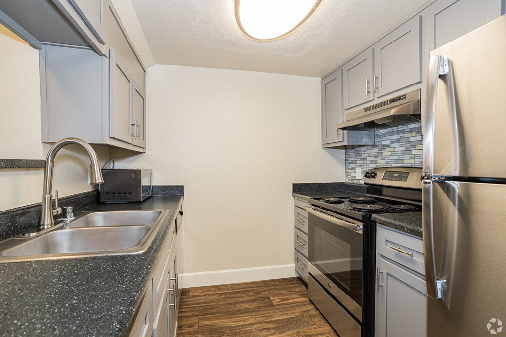 a kitchen with white cabinets and gray countertops