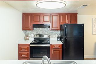 a kitchen with cherry cabinets and black appliances - Photo Gallery