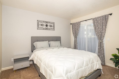 a bedroom with a white bedspread and gray headboard