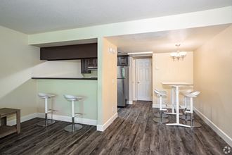 a living room with a bar and a kitchen in the background - Photo Gallery