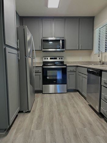 A kitchen with a refrigerator, microwave, oven, and dishwasher