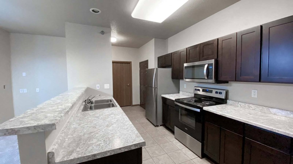 Full kitchen at Amber Crossing with counter, vinyl flooring, view of kitchen, front entrance, and laundry room