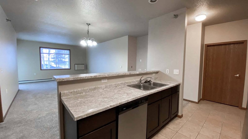 Kitchen at Amber Crossing in Fargo ND with dish washer and view of living room and kitchen, window