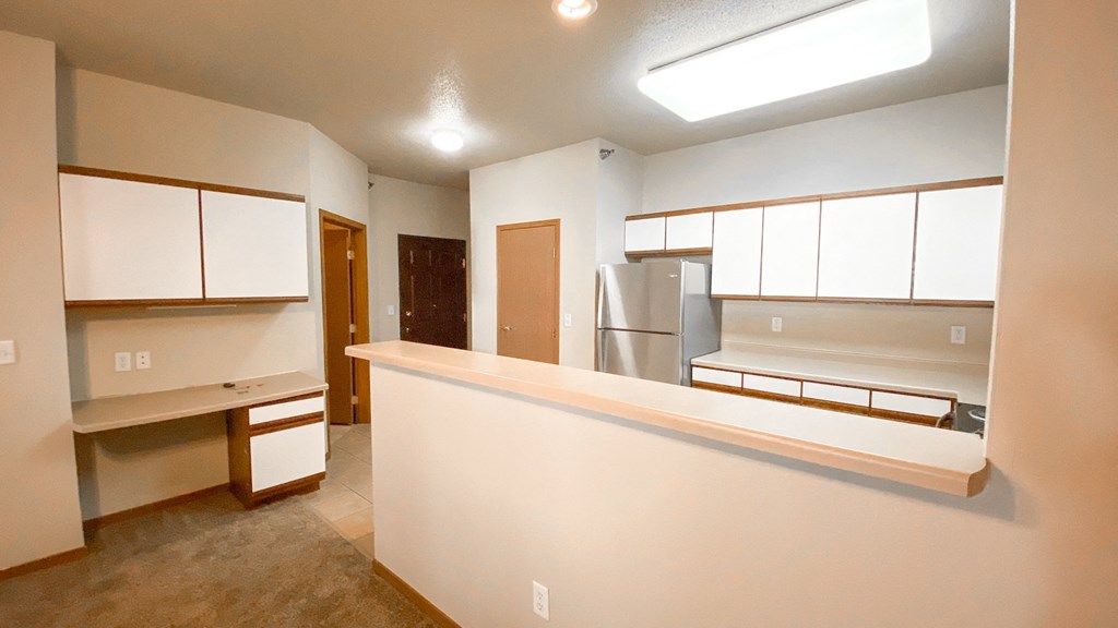 an empty kitchen with white cabinets and a counter top
