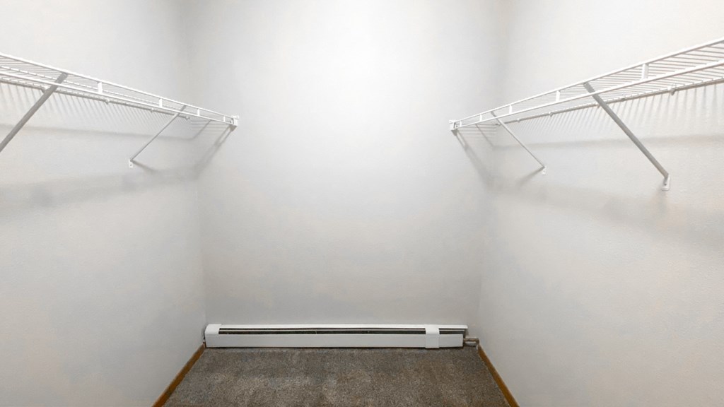 an empty closet with two hanging racks on the wall