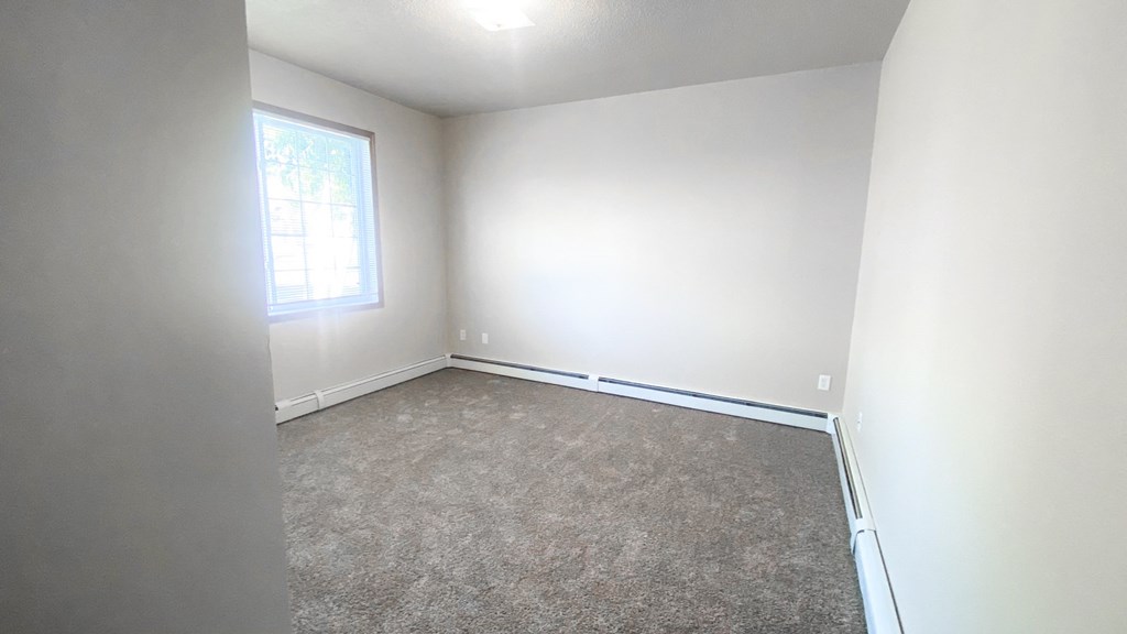 an empty room with white walls and a window