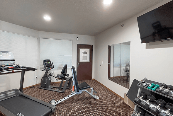 A newly renovated gym with free weights, row machine, treadmill and TV at Amber Crossing Apartments in Fargo, ND.
