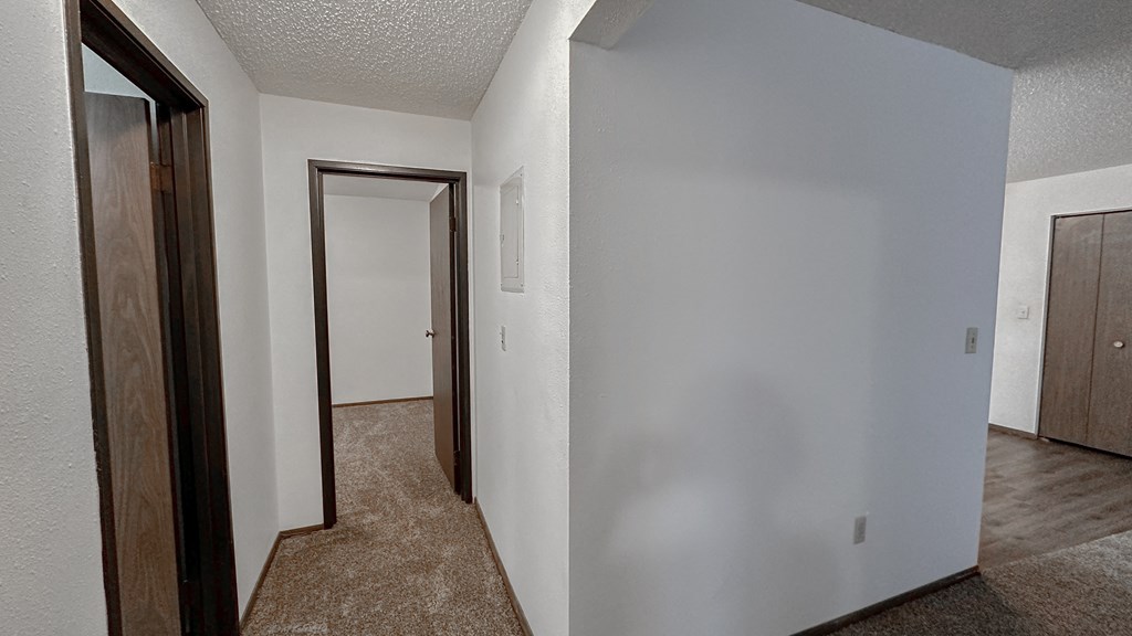 an empty room with a hallway and a door to a closet