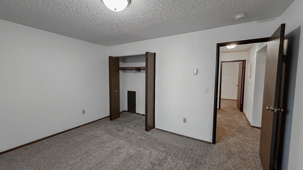 the living room of an empty apartment with a door to the hallway and a closet