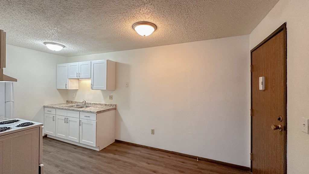 the view of a kitchen with white cabinets and a stove
