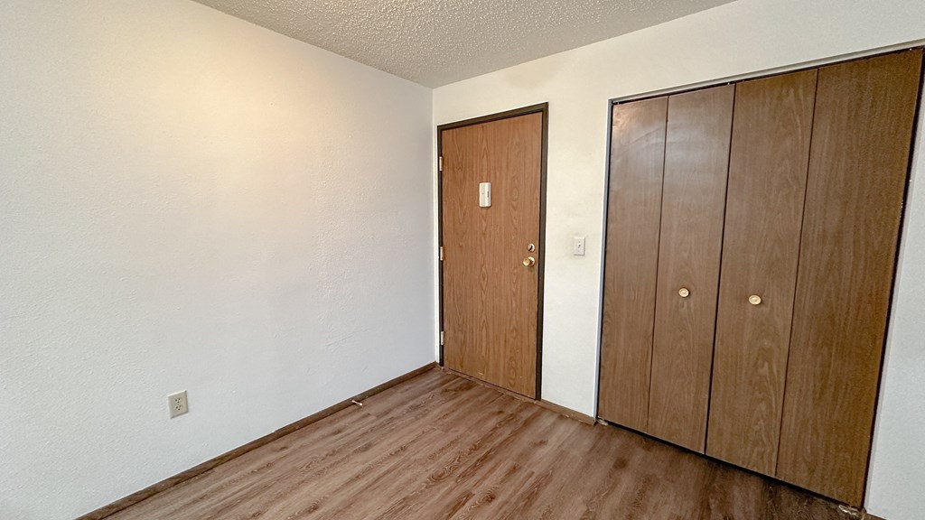 a bedroom with two closet doors and wood flooring