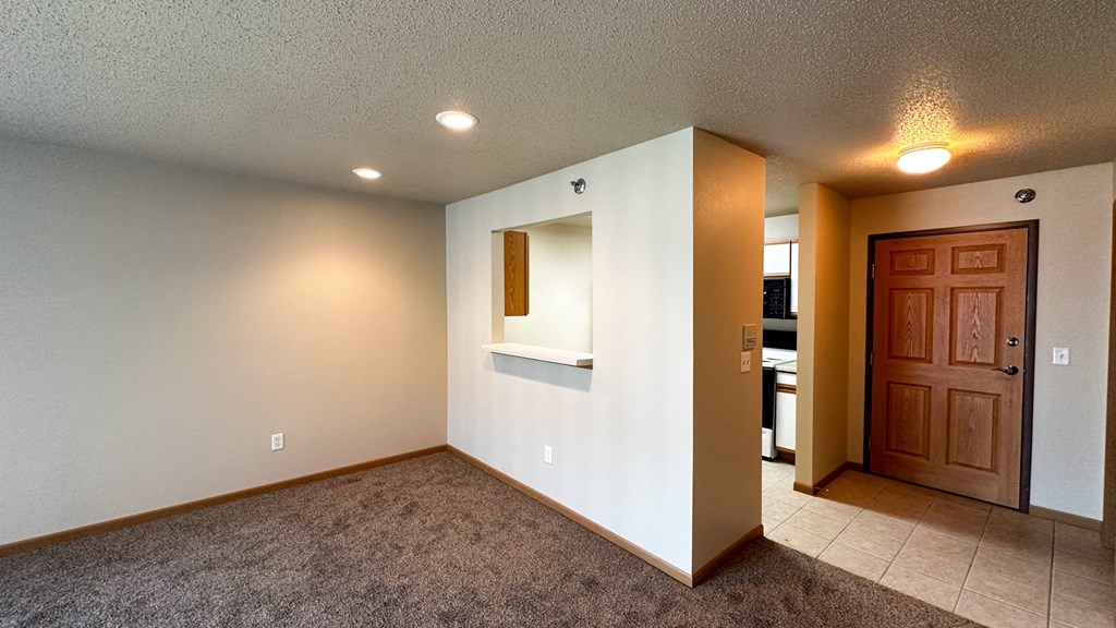 a small living room with a white wall and a brown carpet