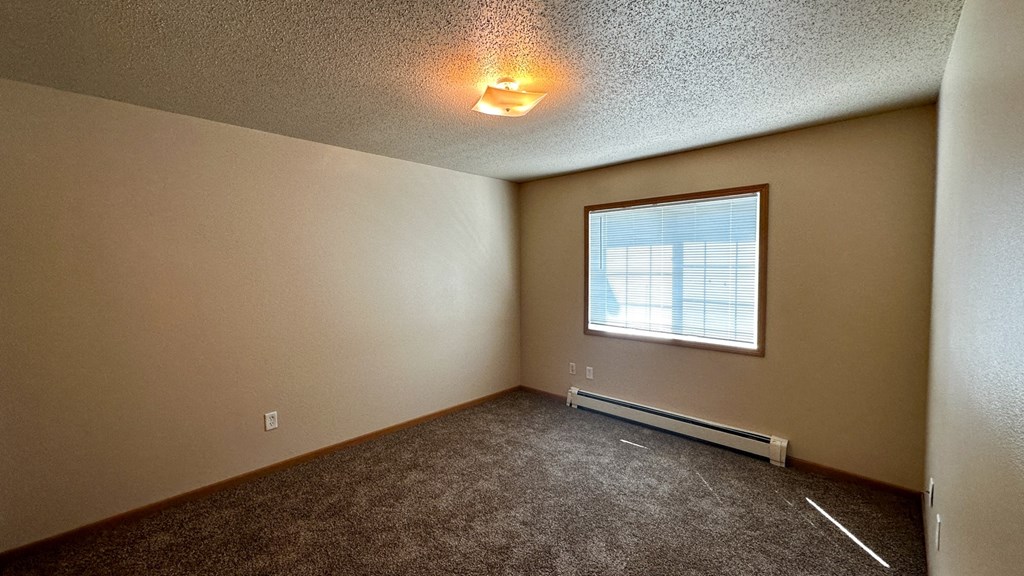 a bedroom with a large window and carpeted flooring