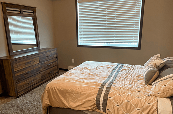 a bedroom with a bed and a dresser and a window