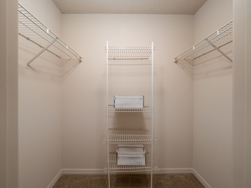 a walk in closet in a small room with white walls and white shelves and racks
