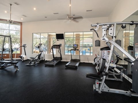 gym with exercise equipment and windows in a room with a ceiling fan
