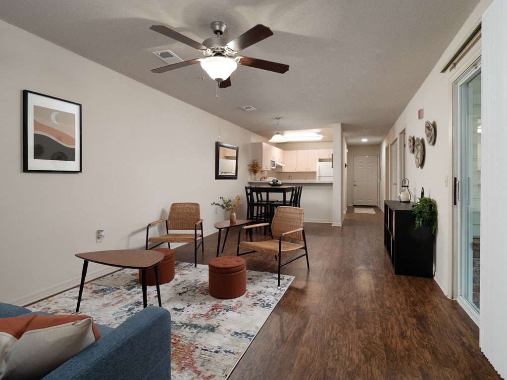 the view of a living room with a ceiling fan and a kitchen