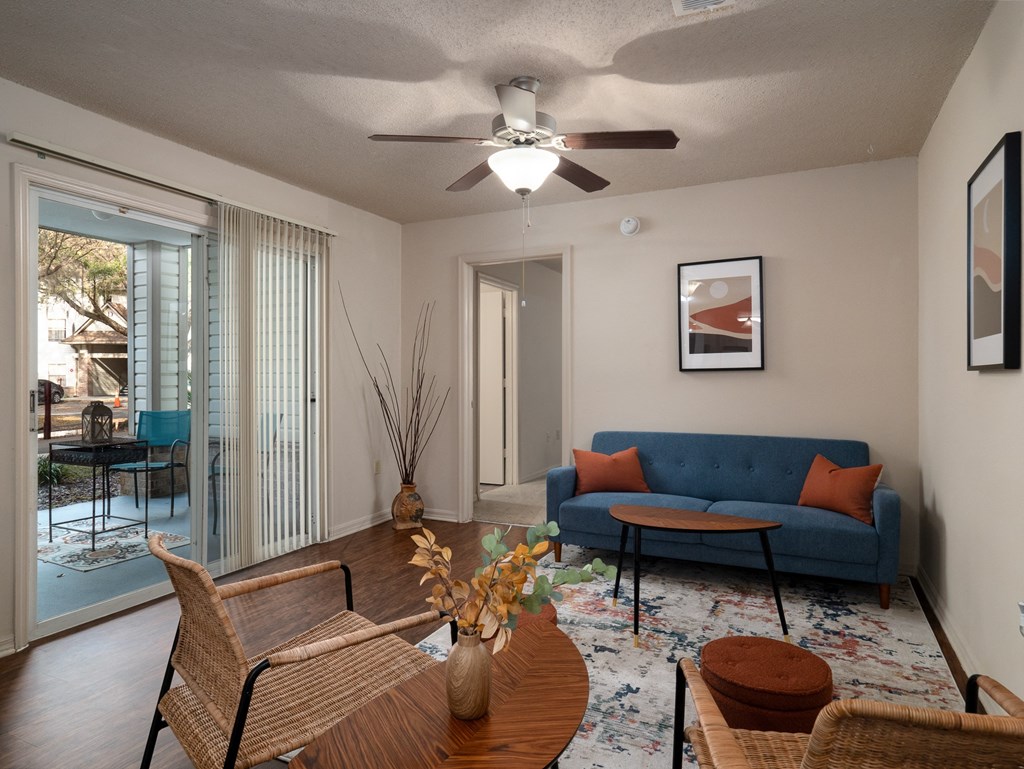 a living room with a blue couch and a ceiling fan