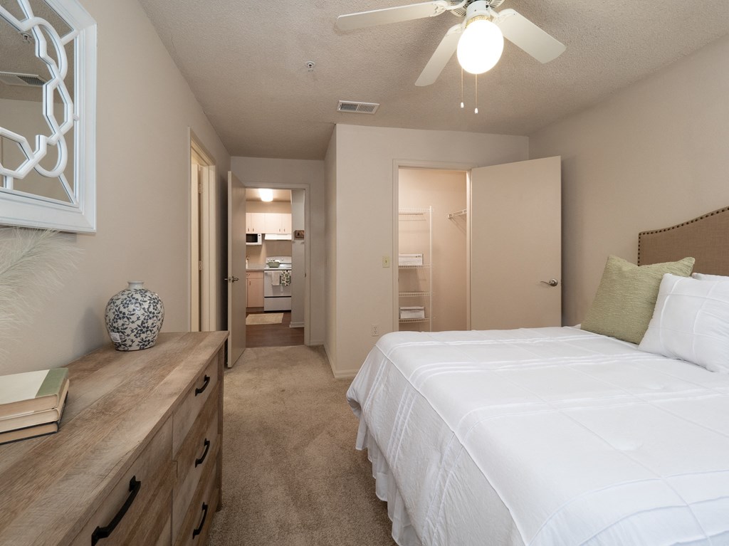 a bedroom with a large white bed and a ceiling fan