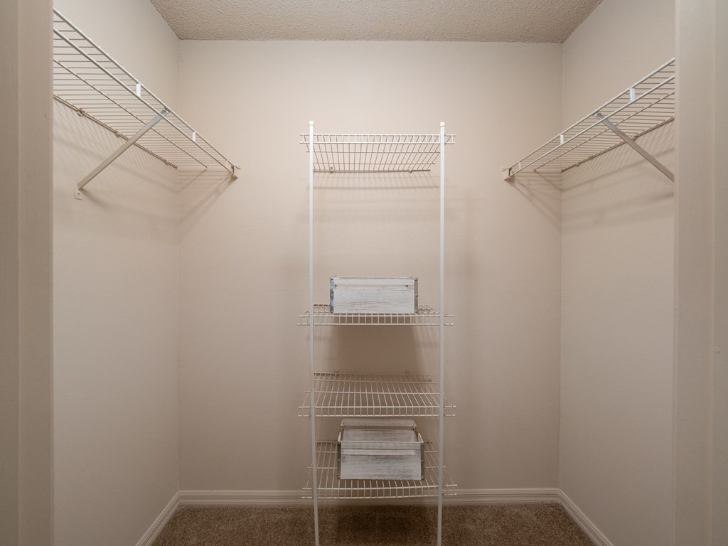 a walk in closet in a small room with white walls and white shelves and racks