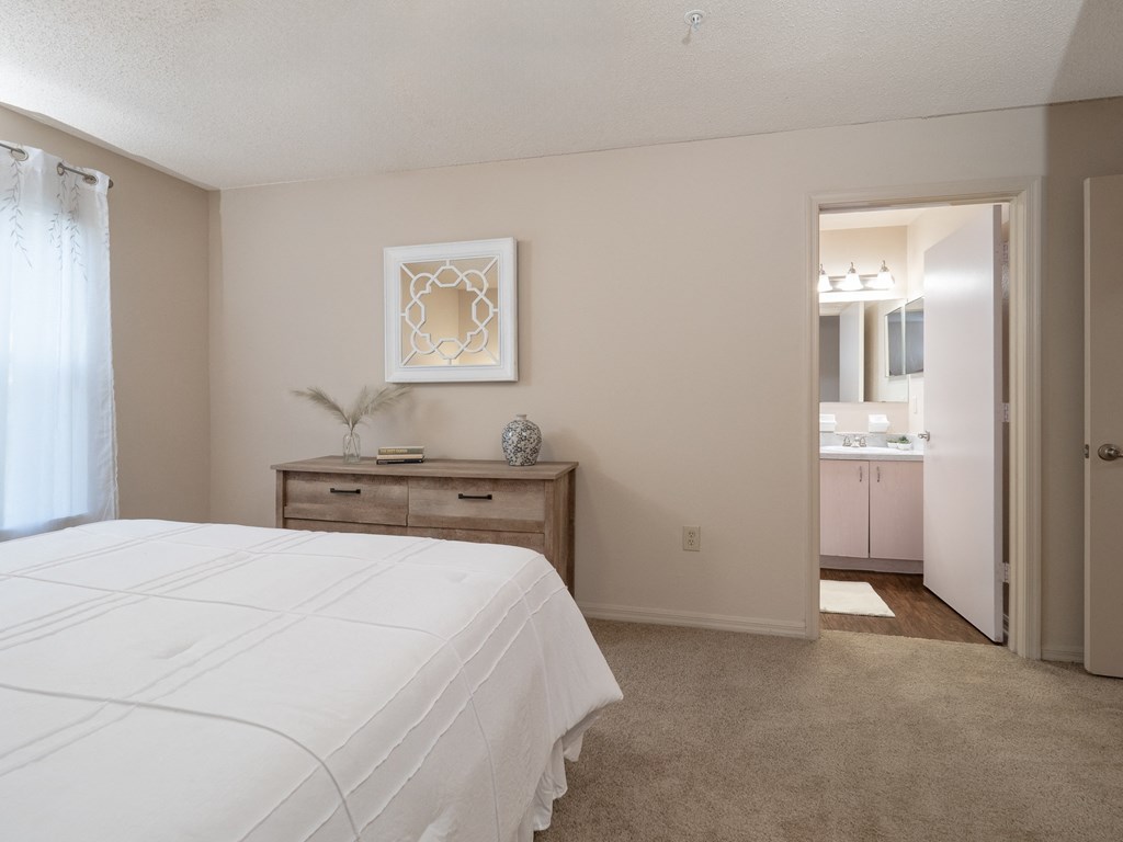 a bedroom with a white bed and a bathroom with a sink