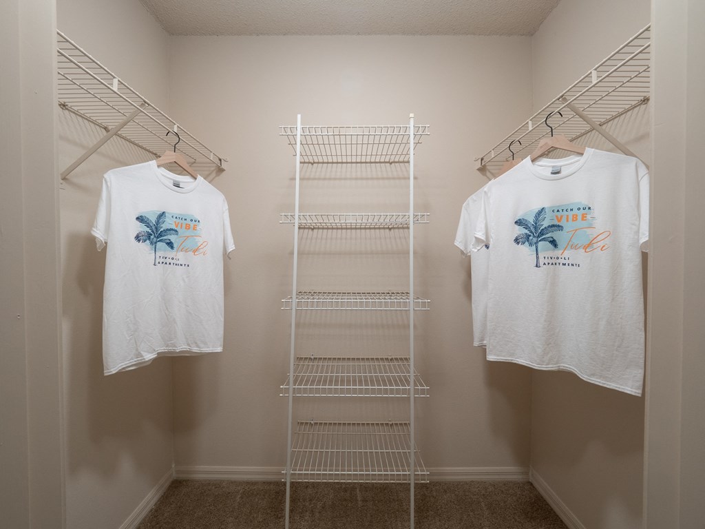 two white shirts hanging on a rack in a closet