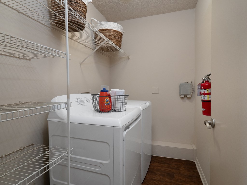 a small laundry room with a washer and dryer and a wire shelf above