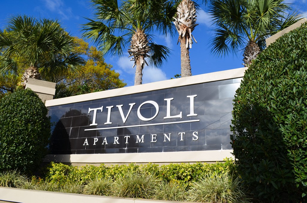 a sign for tivoli apartments in front of palm trees at Tivoli Apartments of Orlando, Oviedo, FL