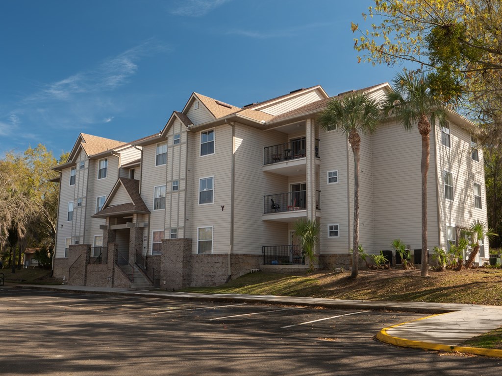 an apartment building on a street with palm trees at Stoneridge Apartments, Gainesville, FL