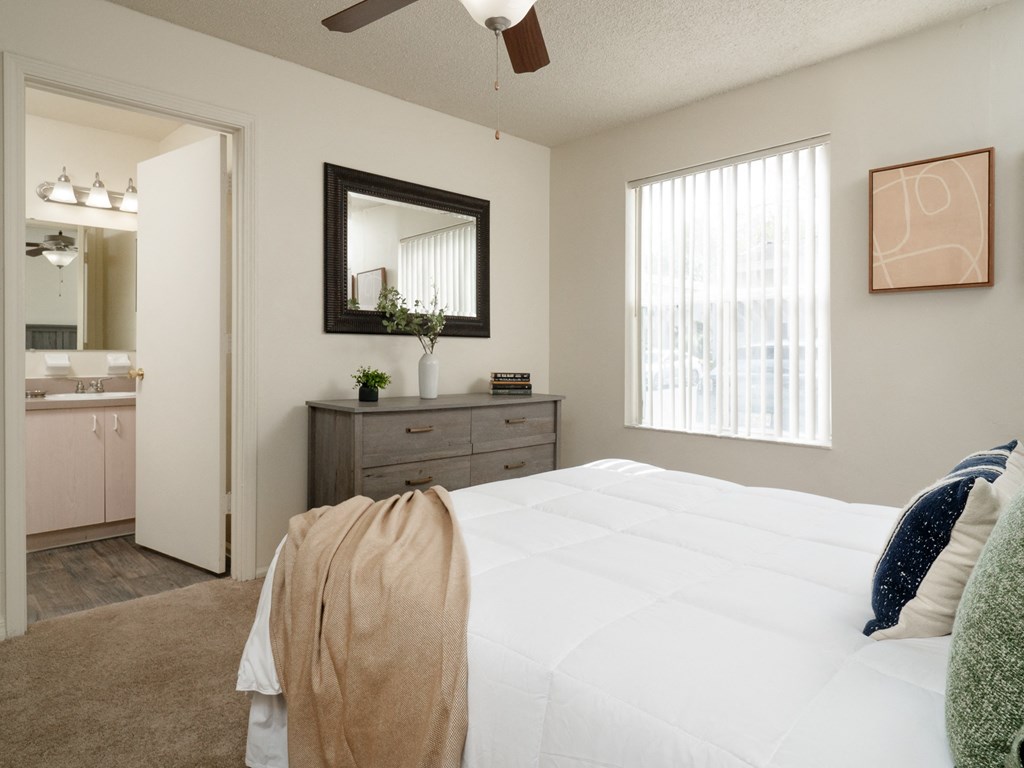 a bedroom with a white bed and a dresser and a bathroom at Stoneridge Apartments, Gainesville, FL