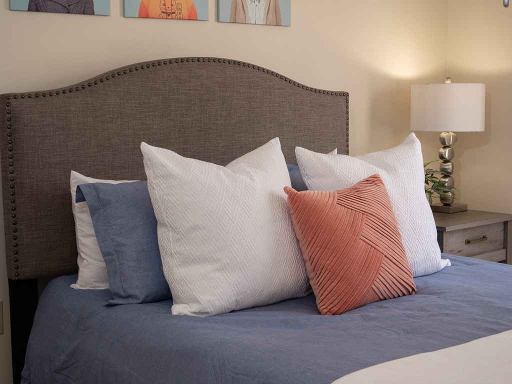 a bed with blue sheets and pillows and a brown headboard at Stoneridge Apartments, Gainesville, Florida
