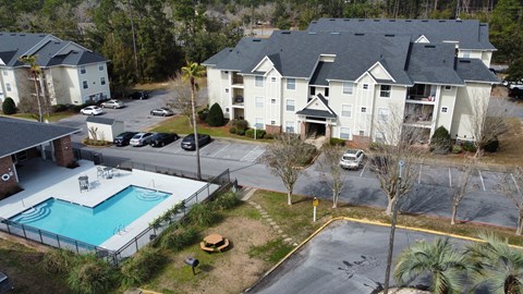 an aerial view of a swimming pool in front of an apartment building at The Fountains Apartments, Pensacola, FL