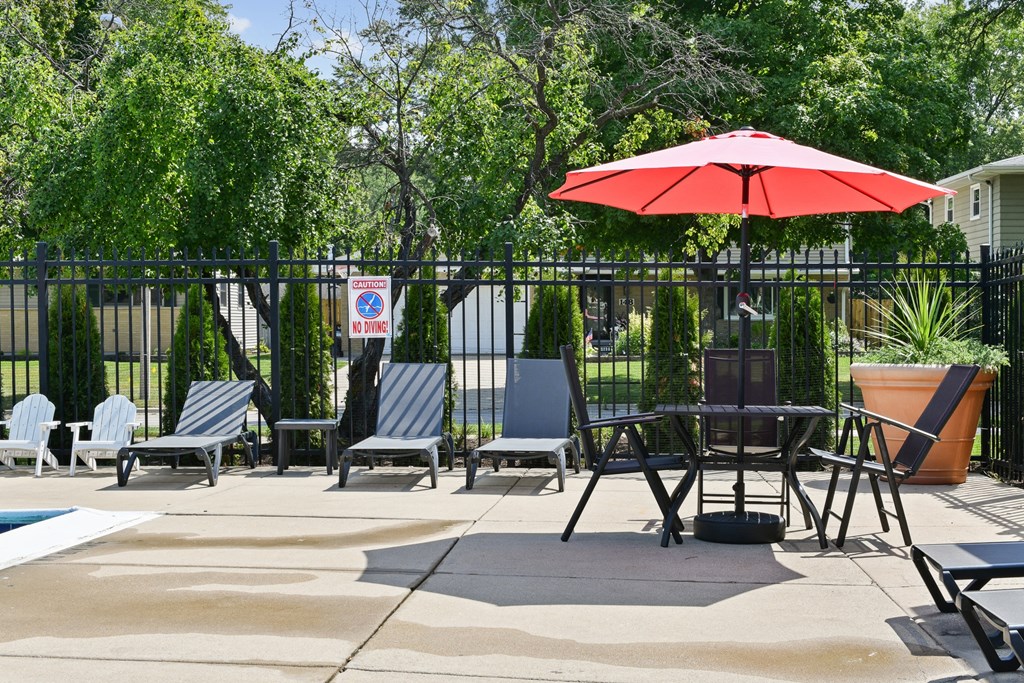 a patio with chairs and a table with an umbrellaat Fox Run Apartments, St. Charles, 60174