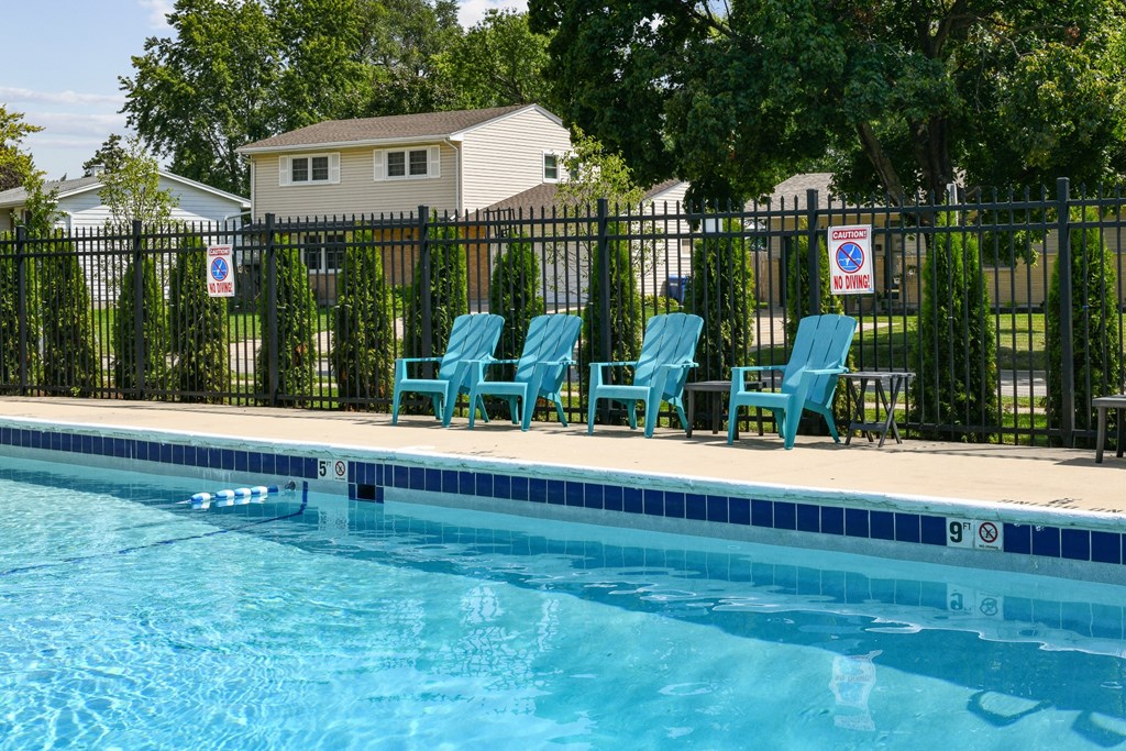 a swimming pool with blue chairs in front of a fenceat Fox Run Apartments, St. Charles, Illinois